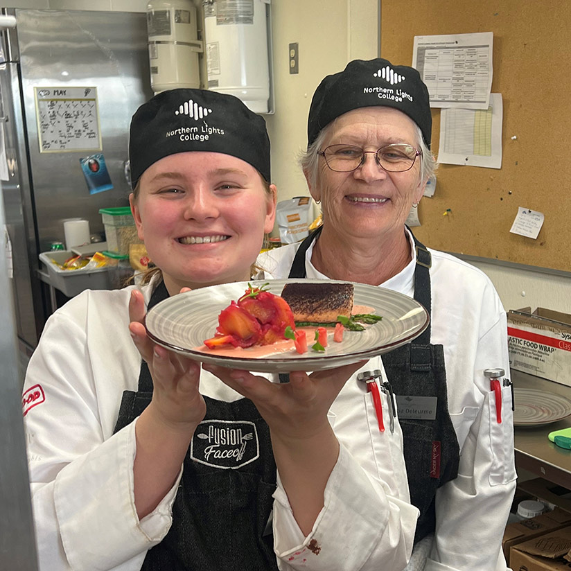 Two chefs show off their salmon dish