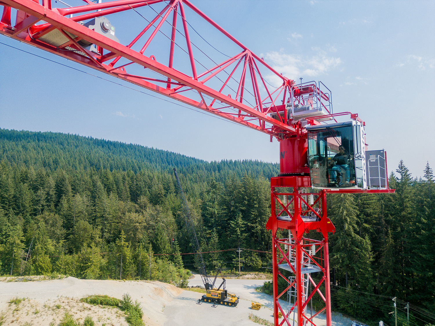 red tower crane with forest and mountains in the background