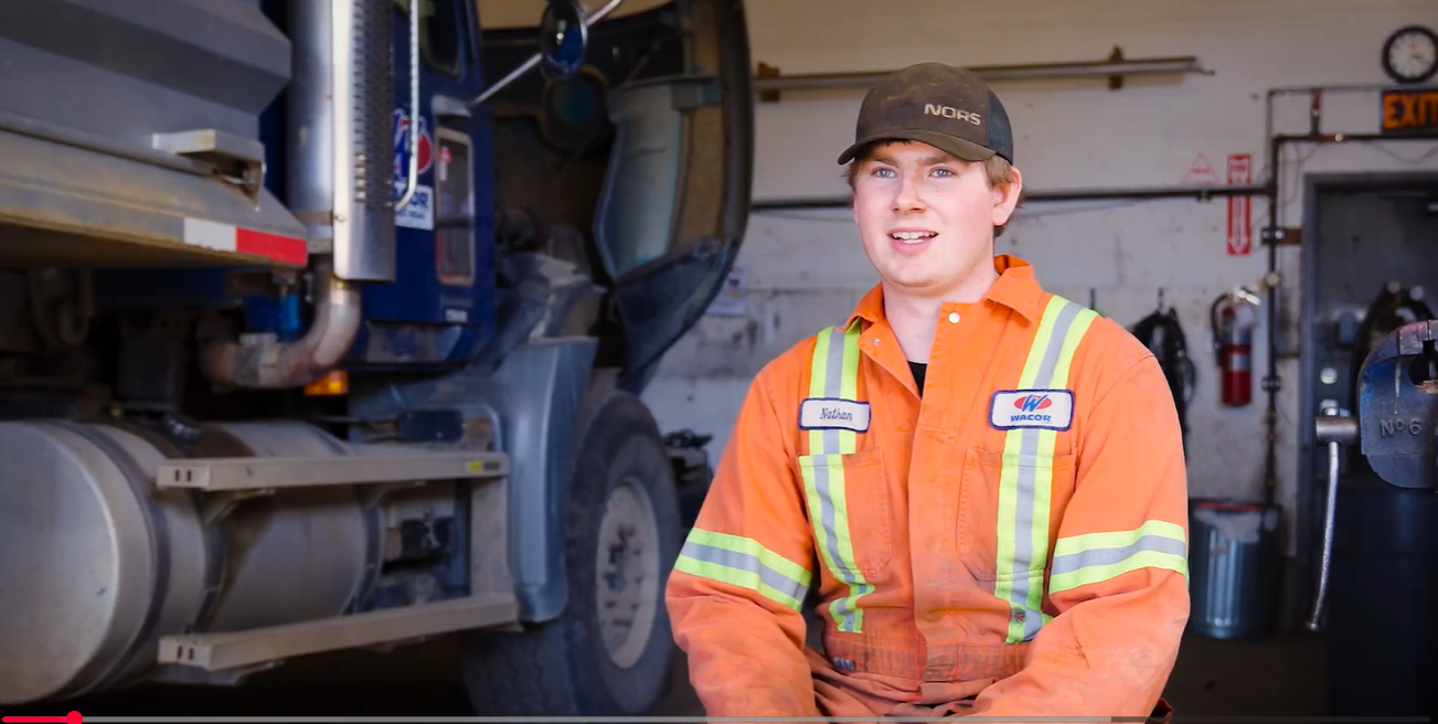 Nathan smiling, sitting in shop with truck behind him