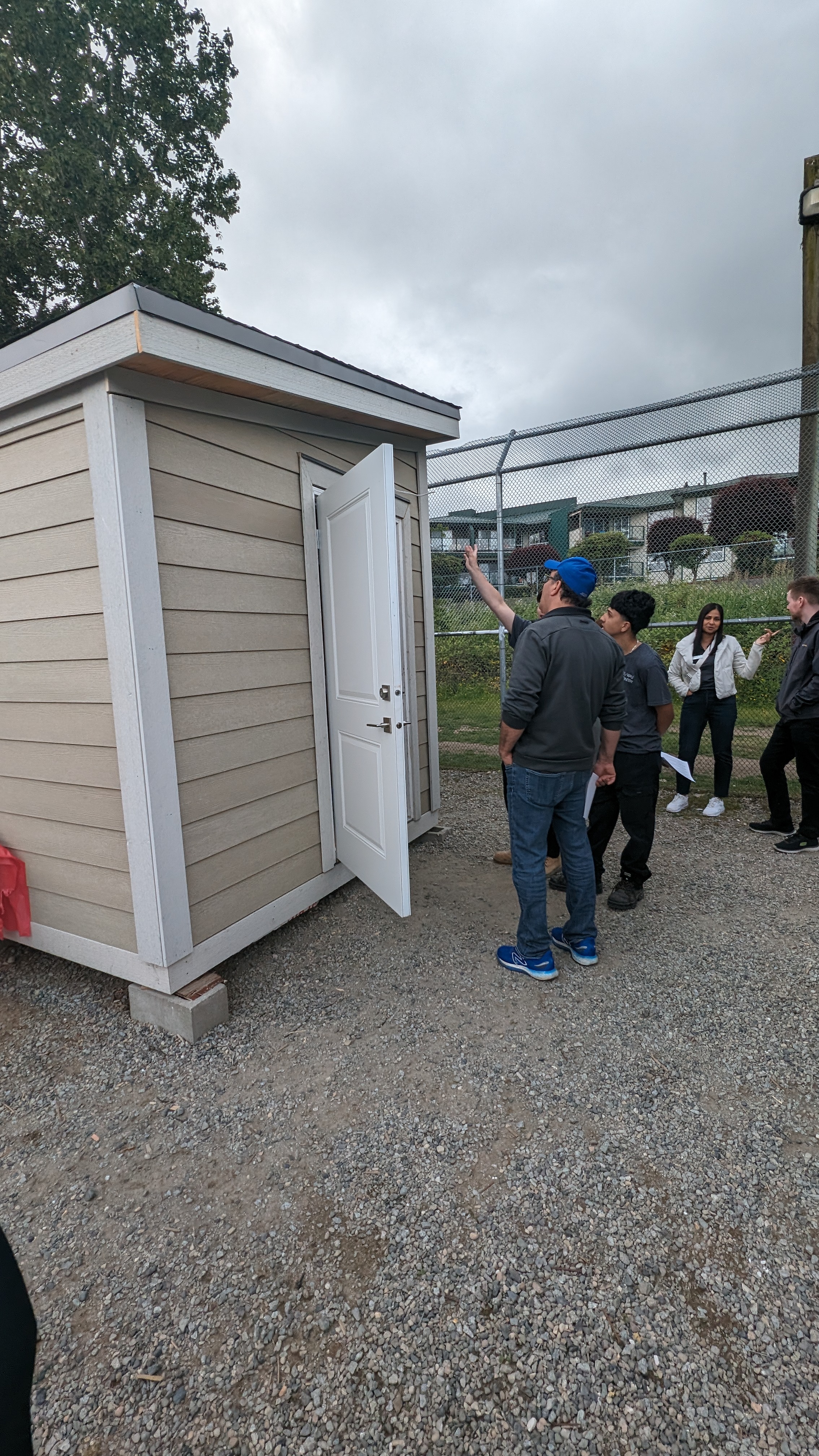 Instructor and student checking out a beige shed with the door open