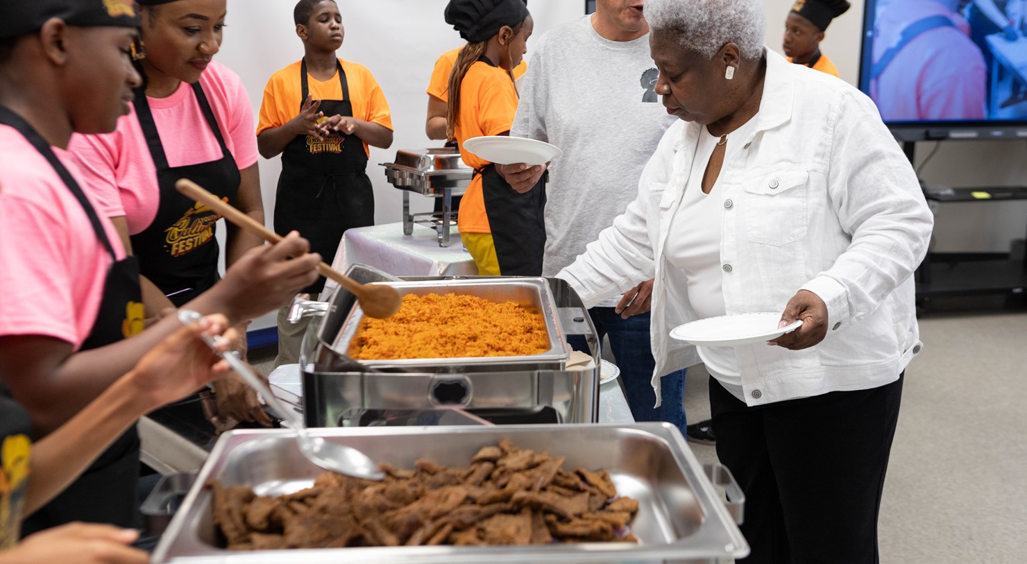 People on either side of a table serving food buffet style