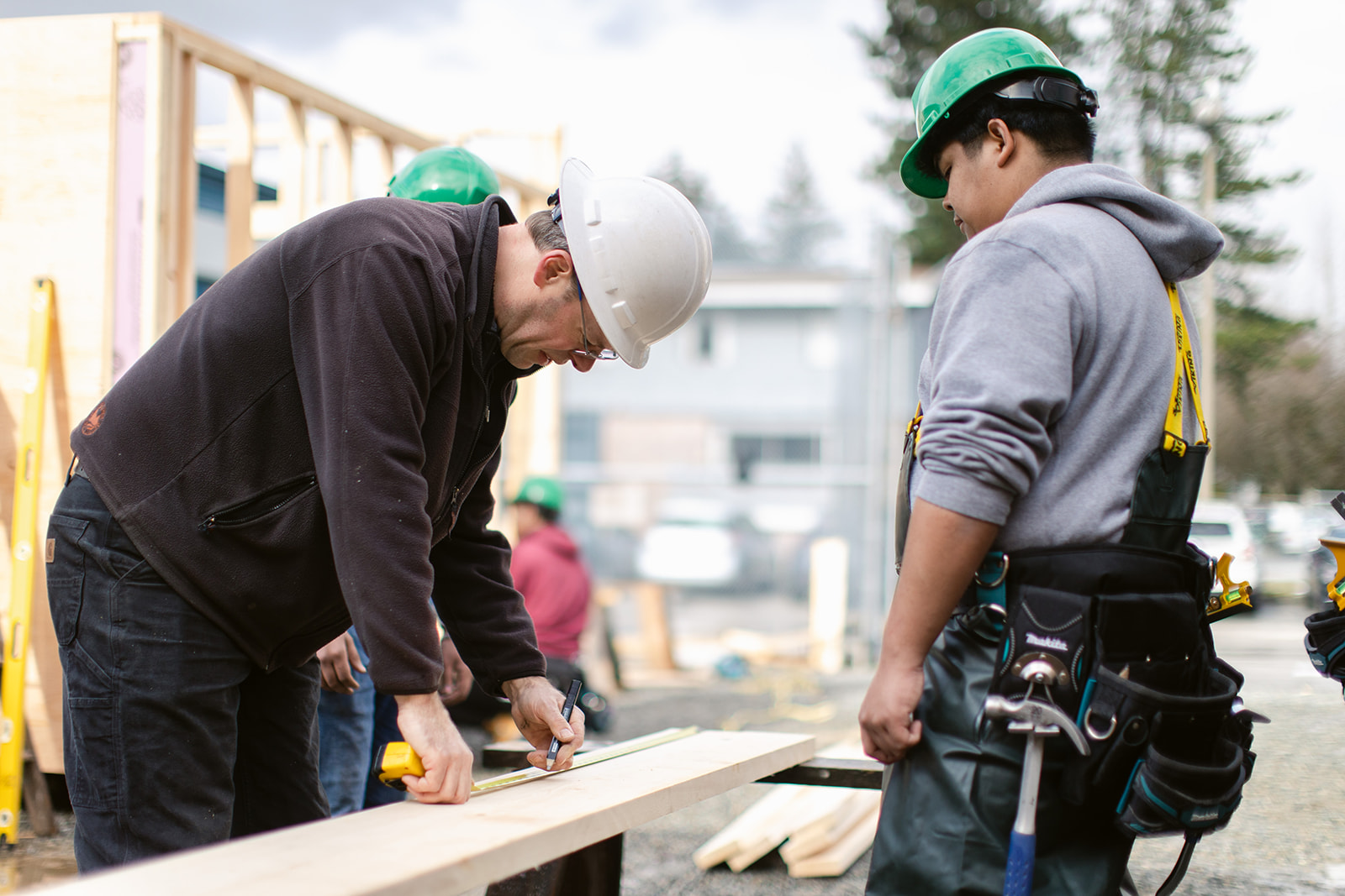 Instructor showing student how to measure the piece of wood