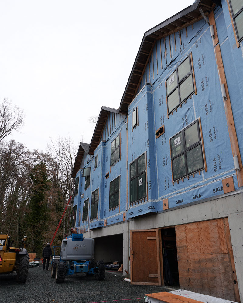 townhouse buildings with cloudy skies in background and blue housewrap