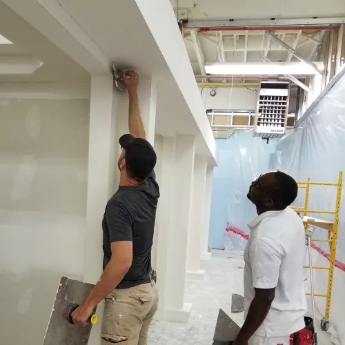 two drywall finishers working on wall