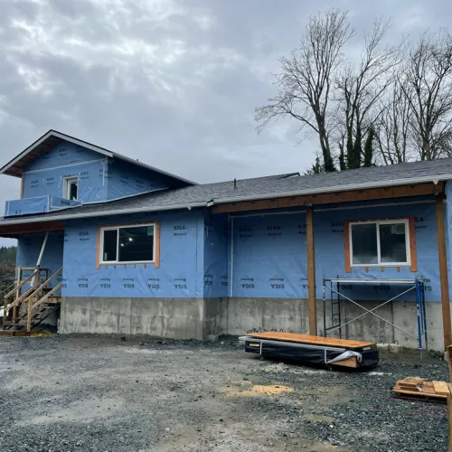 single story home under construction with blue housewrap